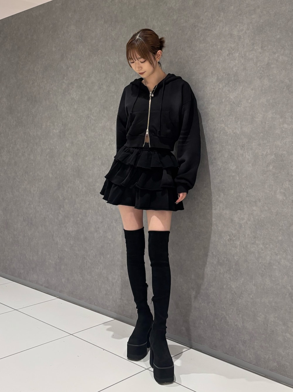 ブラック系のパーカー、ブラック系のスカート、ブラック系のブーツを着用したレディースの秋コーディネートの1枚目の写真