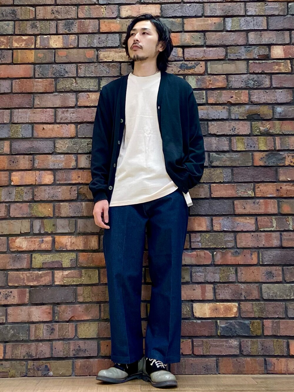 ブラック系のカーディガン/ボレロ、ベージュ系のTシャツ/カットソー、ブルー系のデニムパンツを着用したメンズの秋コーディネートの1枚目の写真