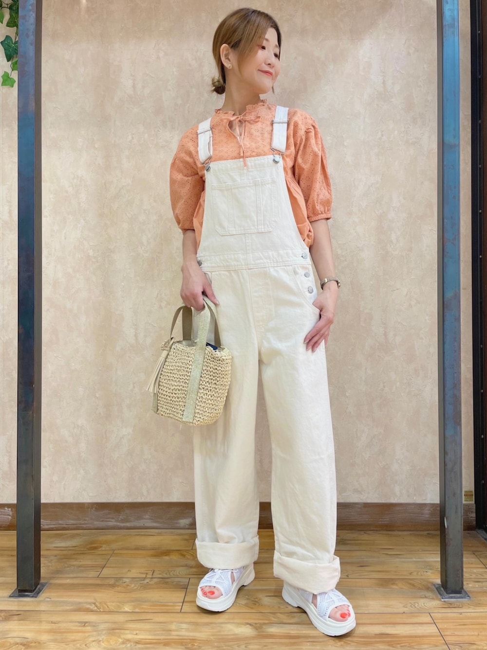 オレンジ系のトップス、ホワイト系のオールインワン・サロペット、ホワイト系のサンダルを着用したレディースの夏コーディネートの1枚目の写真