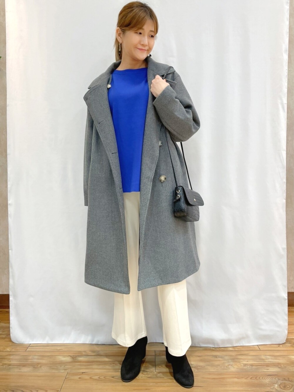 ブルー系のニット/セーター、グレー系のダウンジャケット/コート、ブラック系のショルダーバッグを着用したレディースの秋コーディネートの1枚目の写真