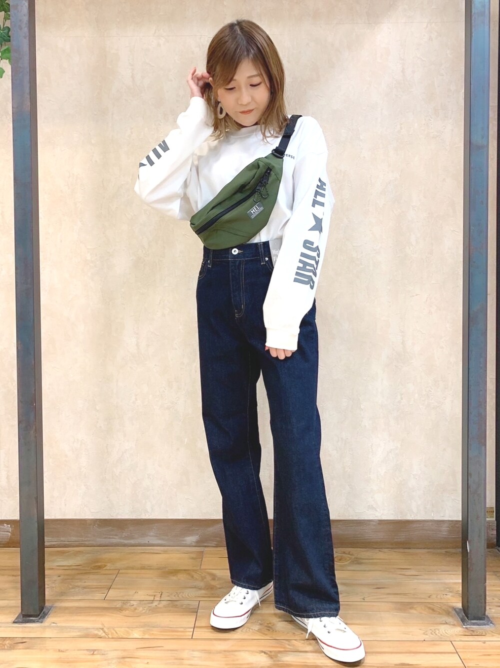 グリーン系のボディバッグ/ウエストポーチ、ホワイト系のTシャツ/カットソー、ブルー系のデニムパンツを着用したレディースの冬コーディネートの1枚目の写真