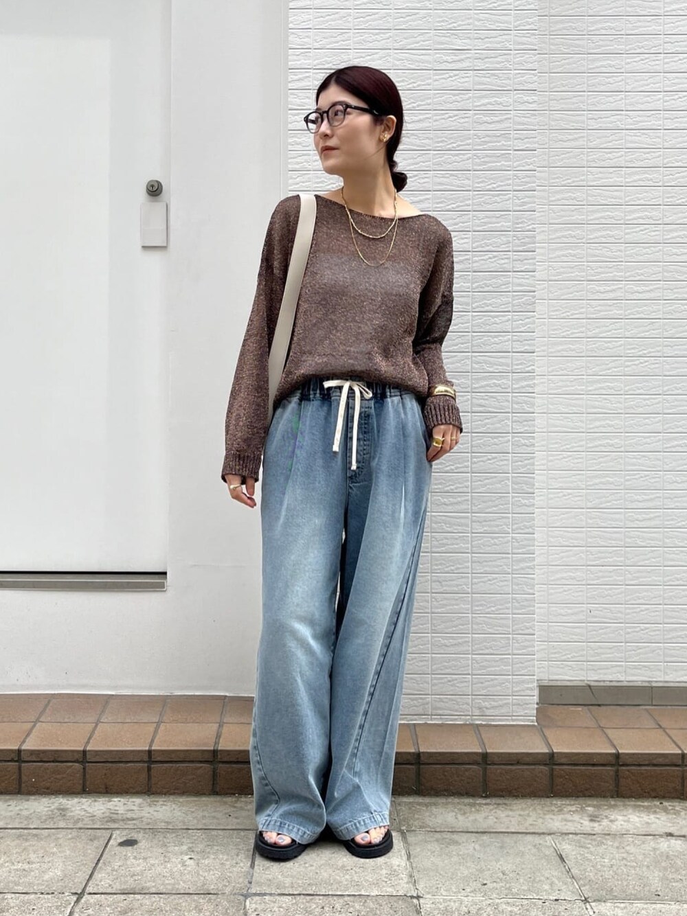 ブラウン系のニット/セーター、ブルー系のデニムパンツ、シルバー系のブーツを着用したレディースの春コーディネートの1枚目の写真