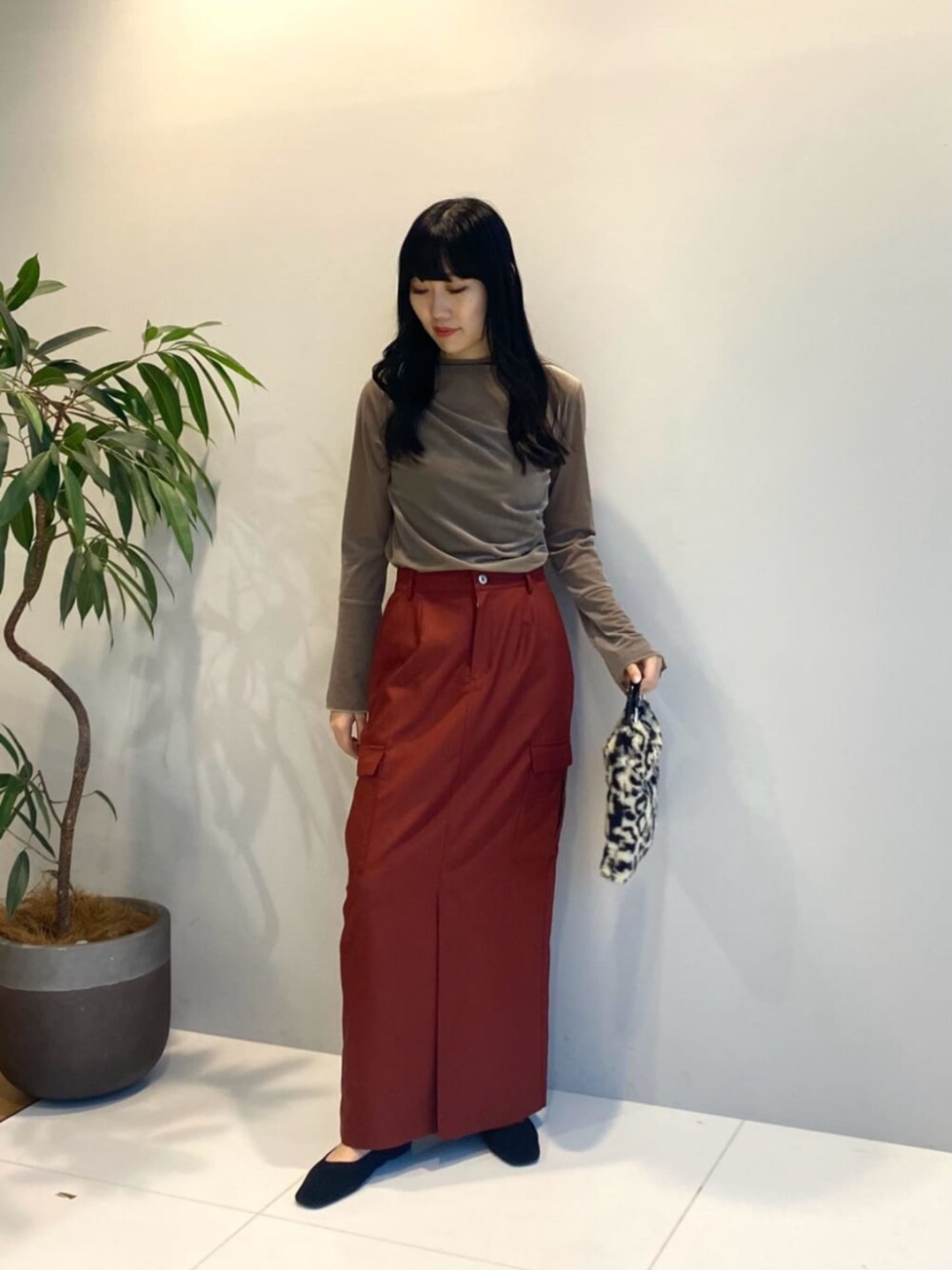 ブラウン系のハンドバッグ、レッド系のスカート、ベージュ系のTシャツ/カットソーを着用したレディースの秋コーディネートの1枚目の写真