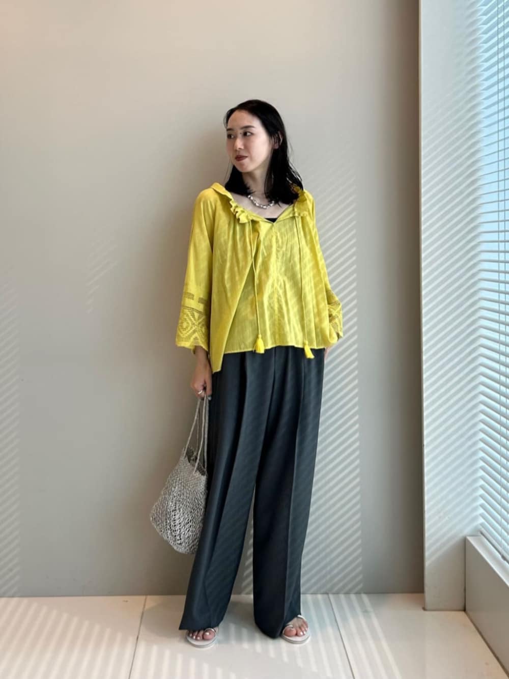 グレー系のその他パンツ、イエロー系のシャツ/ブラウス、シルバー系のハンドバッグを着用したレディースの夏コーディネートの1枚目の写真
