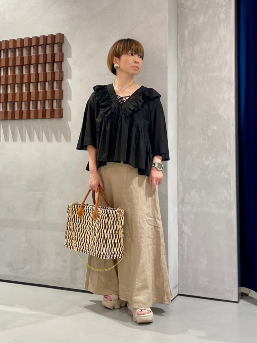 ベージュ系のスカート、ブラック系のシャツ/ブラウス、ブルー系のトートバッグを着用したレディースの夏コーディネートの1枚目の写真