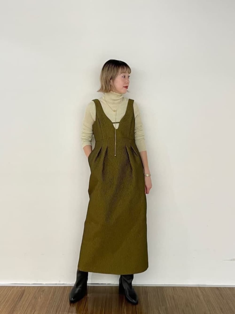 ブラック系のブーツ、グリーン系のワンピース、ゴールド系のニット/セーターを着用したレディースの秋コーディネートの1枚目の写真