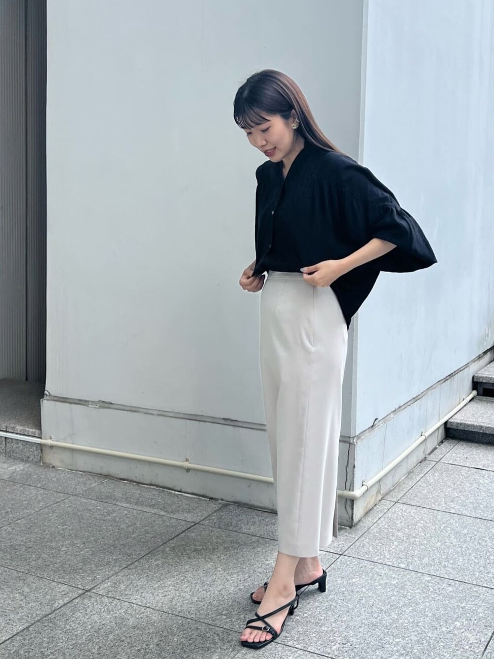 ブラック系のサンダル、ベージュ系のスカート、ブラック系のシャツ/ブラウスを着用したレディースの夏コーディネートの1枚目の写真