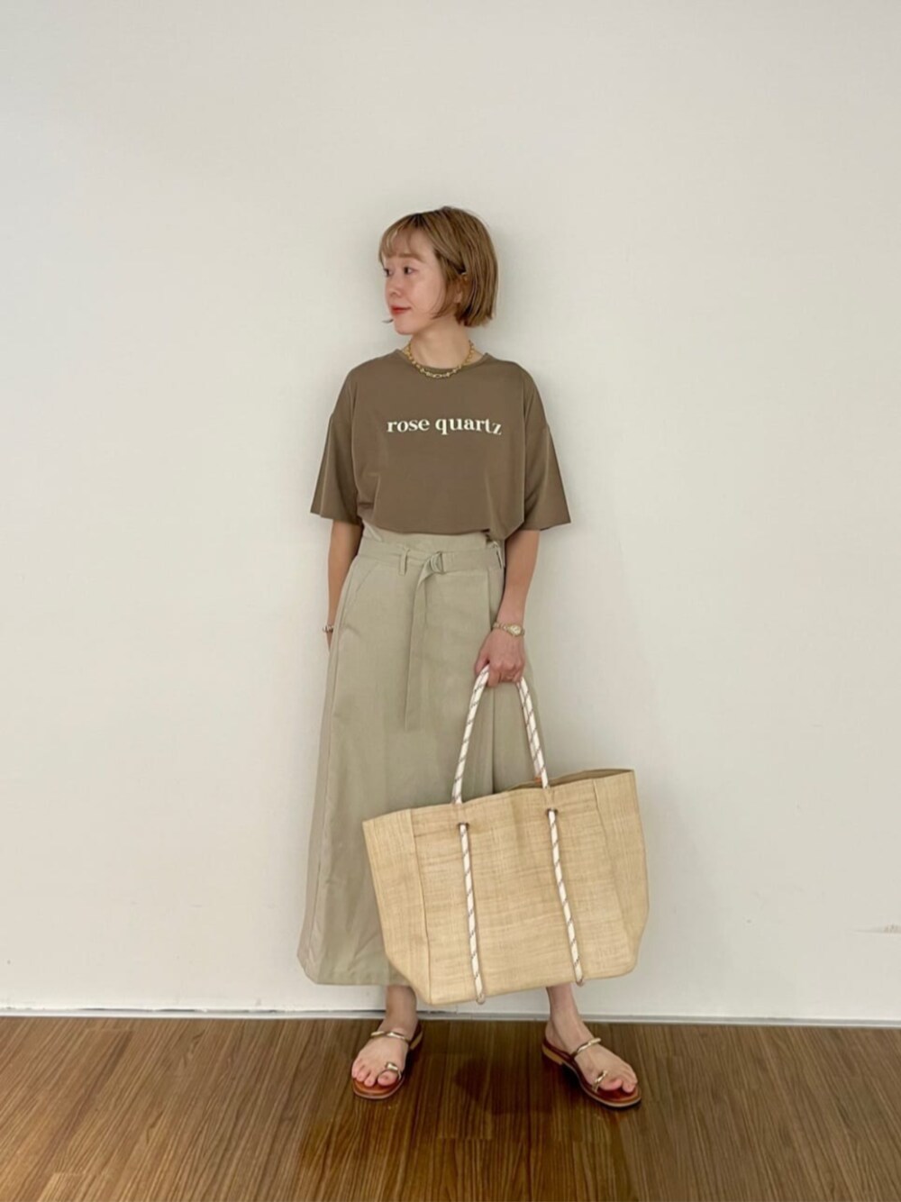 ベージュ系のスカート、ベージュ系のトートバッグ、ブラウン系のTシャツ/カットソーを着用したレディースの夏コーディネートの1枚目の写真