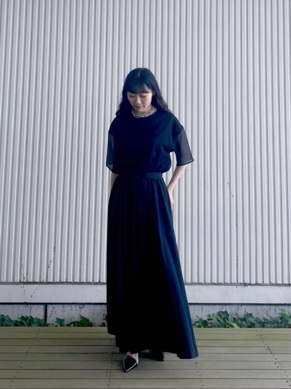 ブラック系のスカート、ブラック系のTシャツ/カットソー、ホワイト系のネックレスを着用したレディースの夏コーディネートの1枚目の写真