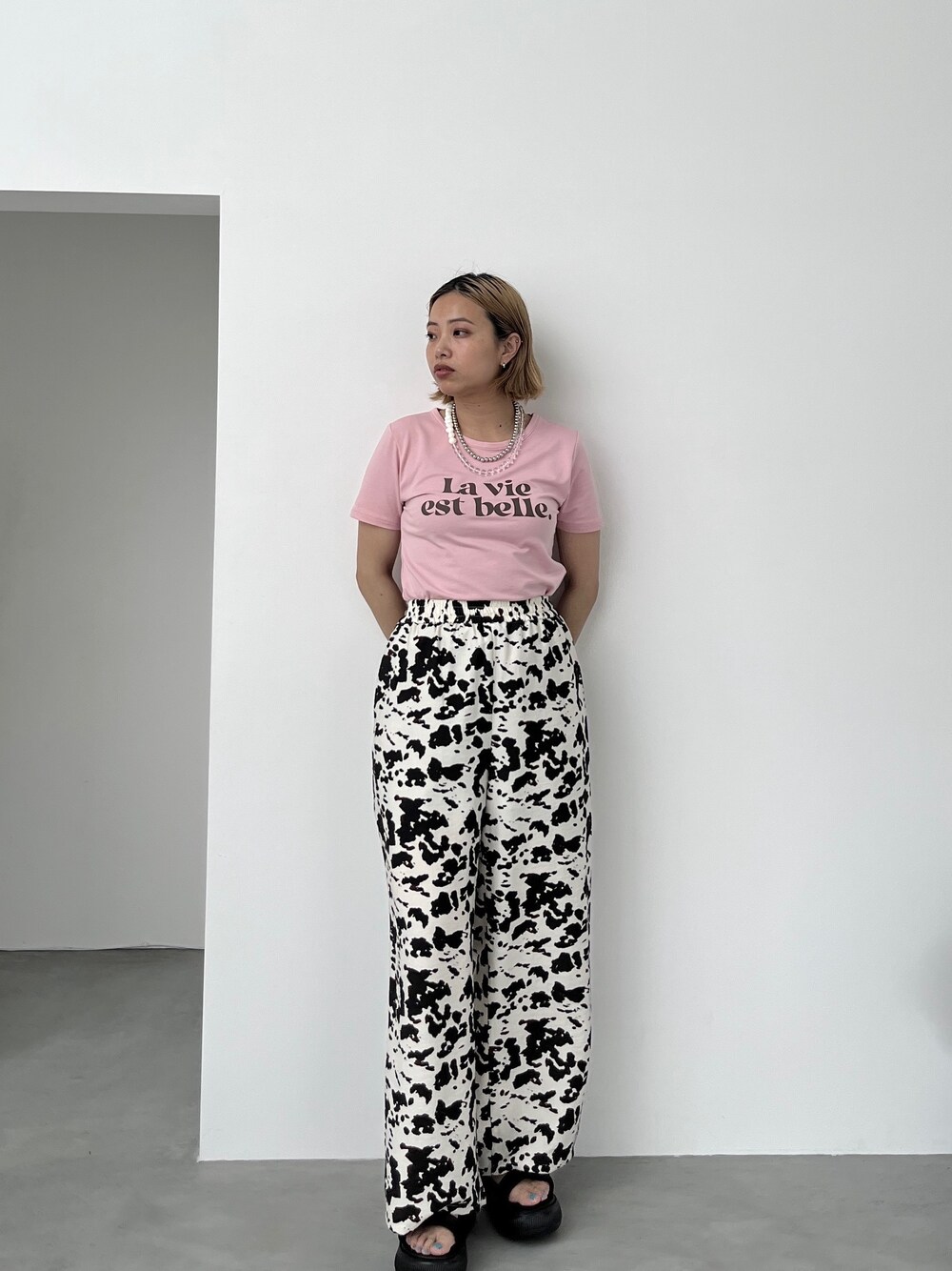 ピンク系のTシャツ/カットソー、ベージュ系のその他パンツ、ブラック系のサンダルを着用したレディースの夏コーディネートの1枚目の写真