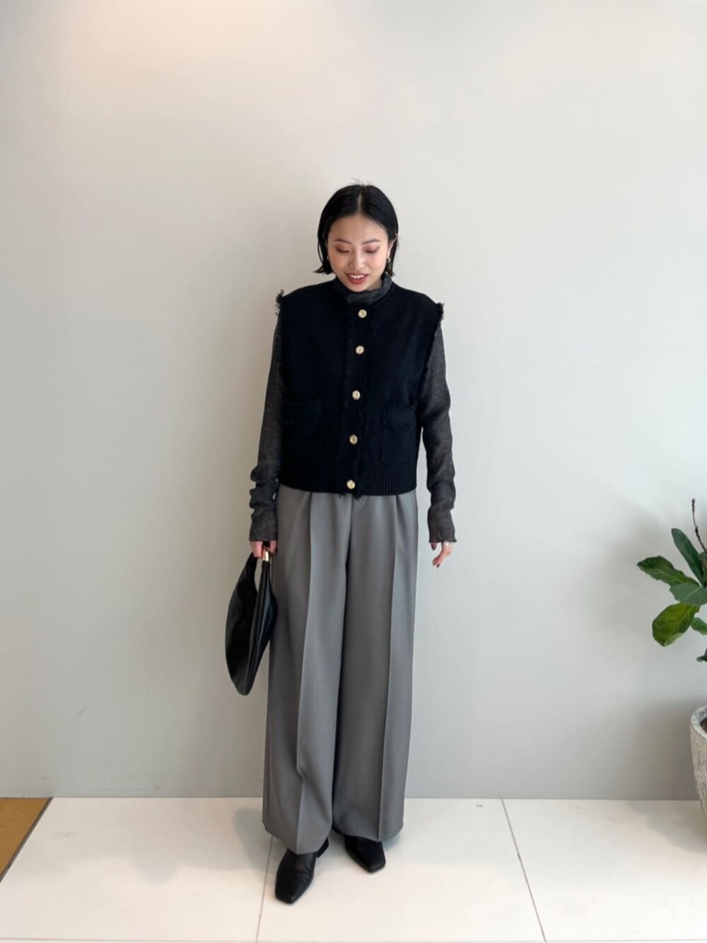 ブラック系のハンドバッグ、グレー系のその他パンツ、ブラック系のベストを着用したレディースの春コーディネートの1枚目の写真
