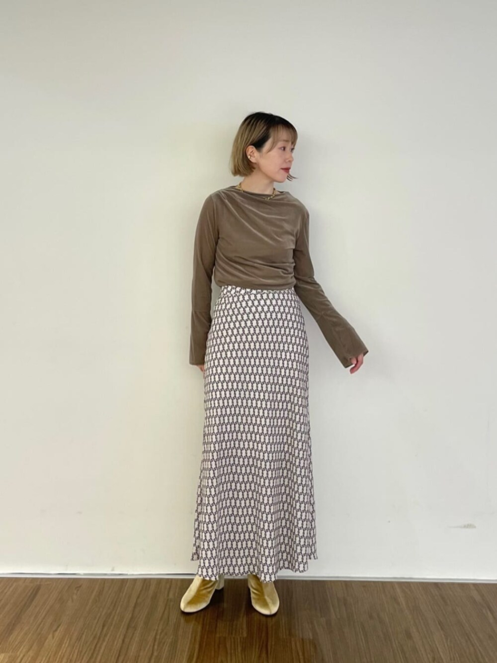 ベージュ系のスカート、ベージュ系のTシャツ/カットソーを着用したレディースの秋コーディネートの1枚目の写真