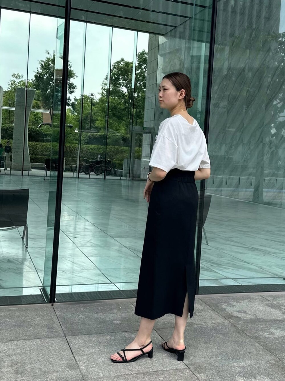 ブラック系のスカート、ホワイト系のTシャツ/カットソー、ブラック系のサンダルを着用したレディースの夏コーディネートの1枚目の写真