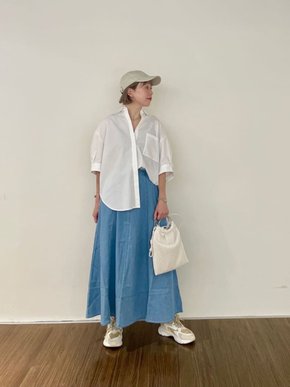 ホワイト系のハンドバッグ、ブルー系のスカート、ホワイト系のシャツ/ブラウスを着用したレディースの夏コーディネートの1枚目の写真