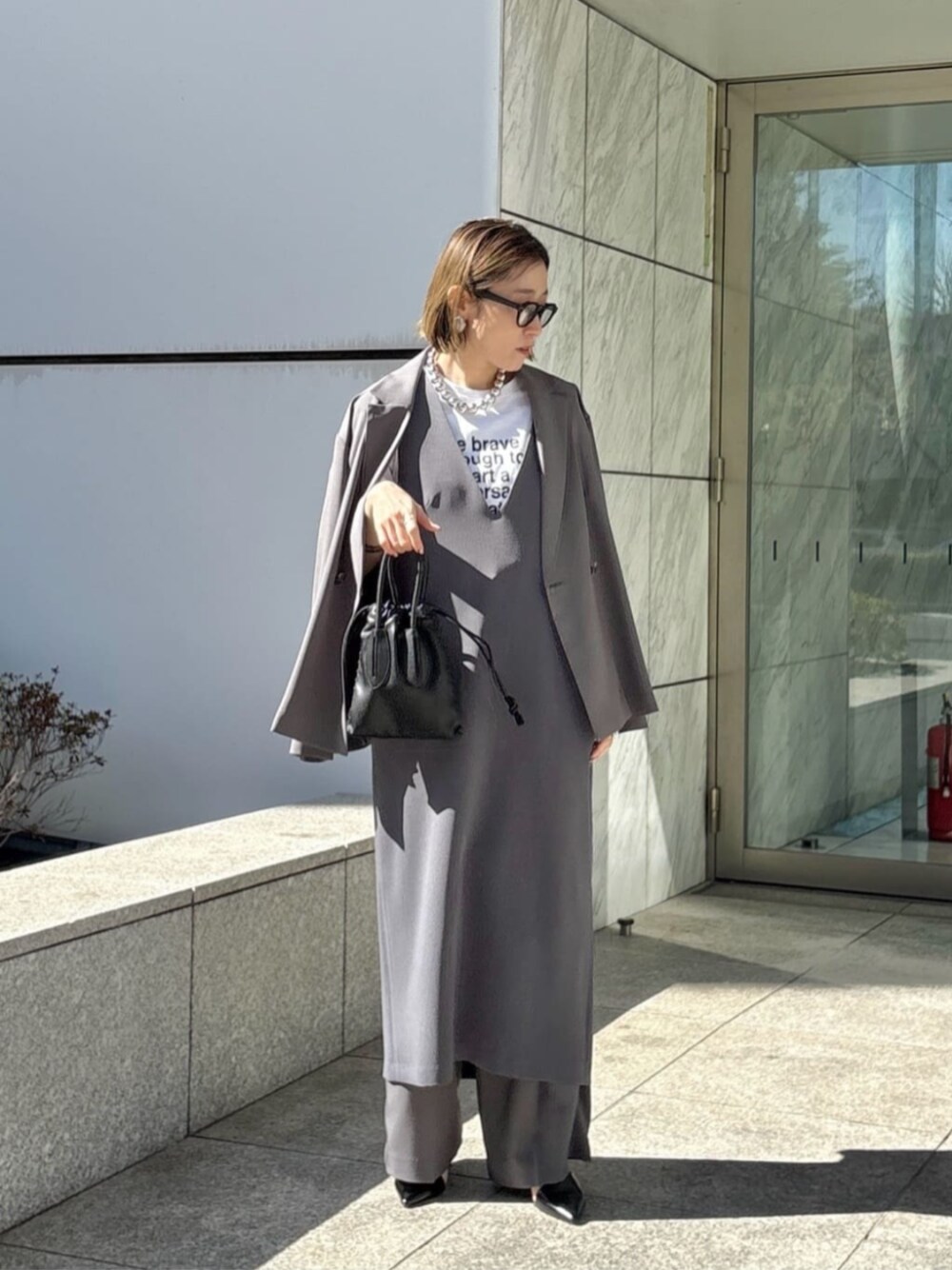 グレー系のその他パンツ、グレー系のワンピース、ホワイト系のTシャツ/カットソーを着用したレディースの春コーディネートの1枚目の写真