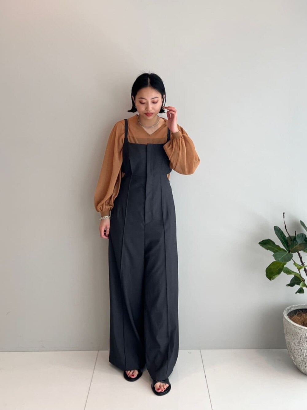 イエロー系のニット/セーター、グレー系のサロペット/オーバーオールを着用したレディースの春コーディネートの1枚目の写真