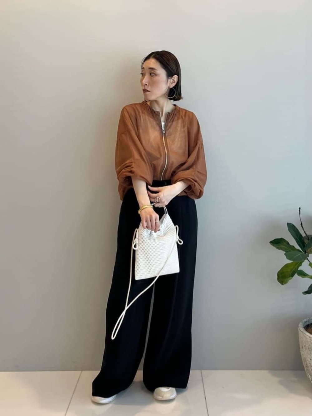ブラック系のその他パンツ、ブラウン系のブルゾン、ホワイト系のハンドバッグを着用したレディースの春コーディネートの1枚目の写真
