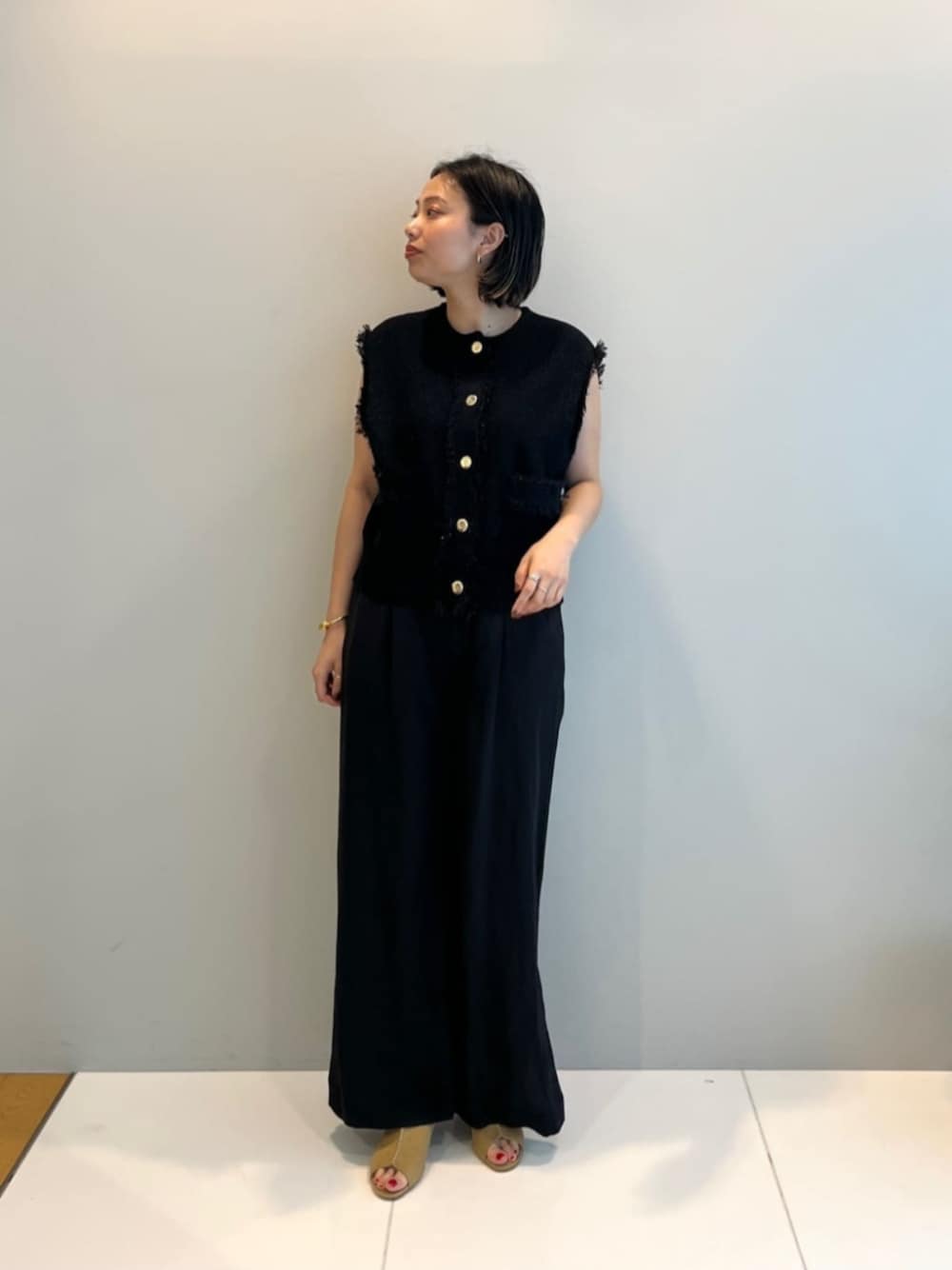 ブラック系のその他パンツ、ブラック系のベスト、ベージュ系のサンダルを着用したレディースの春コーディネートの1枚目の写真