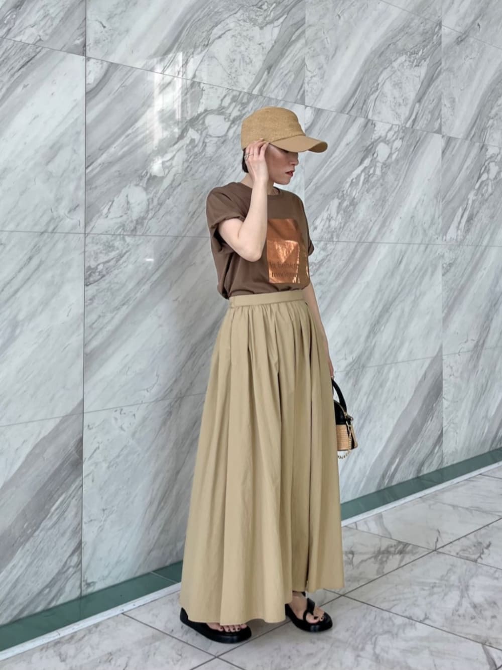 グリーン系のTシャツ/カットソー、ベージュ系のスカート、ベージュ系のキャップを着用したレディースの夏コーディネートの1枚目の写真