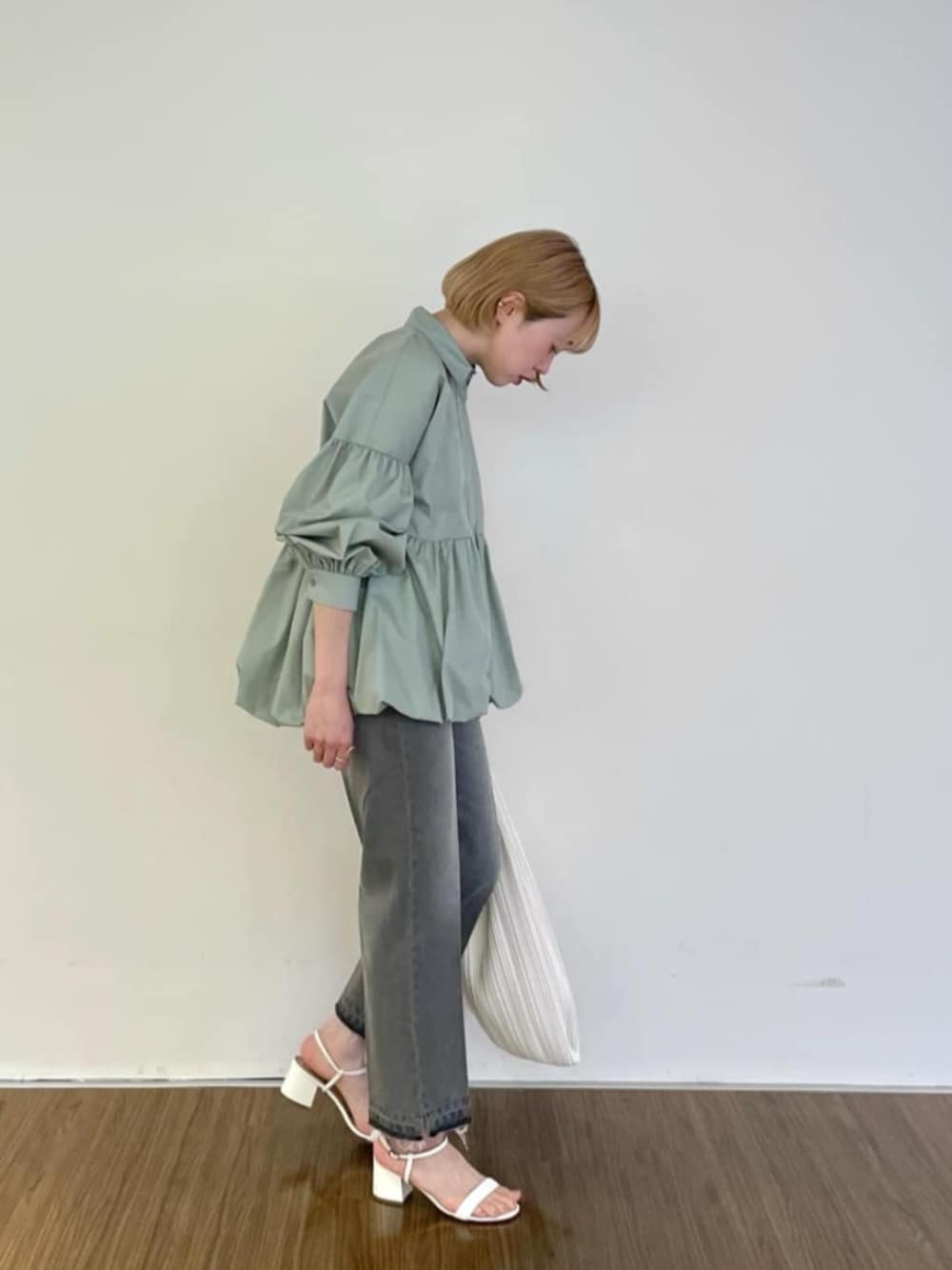 グレー系のデニムパンツ、グリーン系のシャツ/ブラウス、ホワイト系のトートバッグを着用したレディースの春コーディネートの1枚目の写真