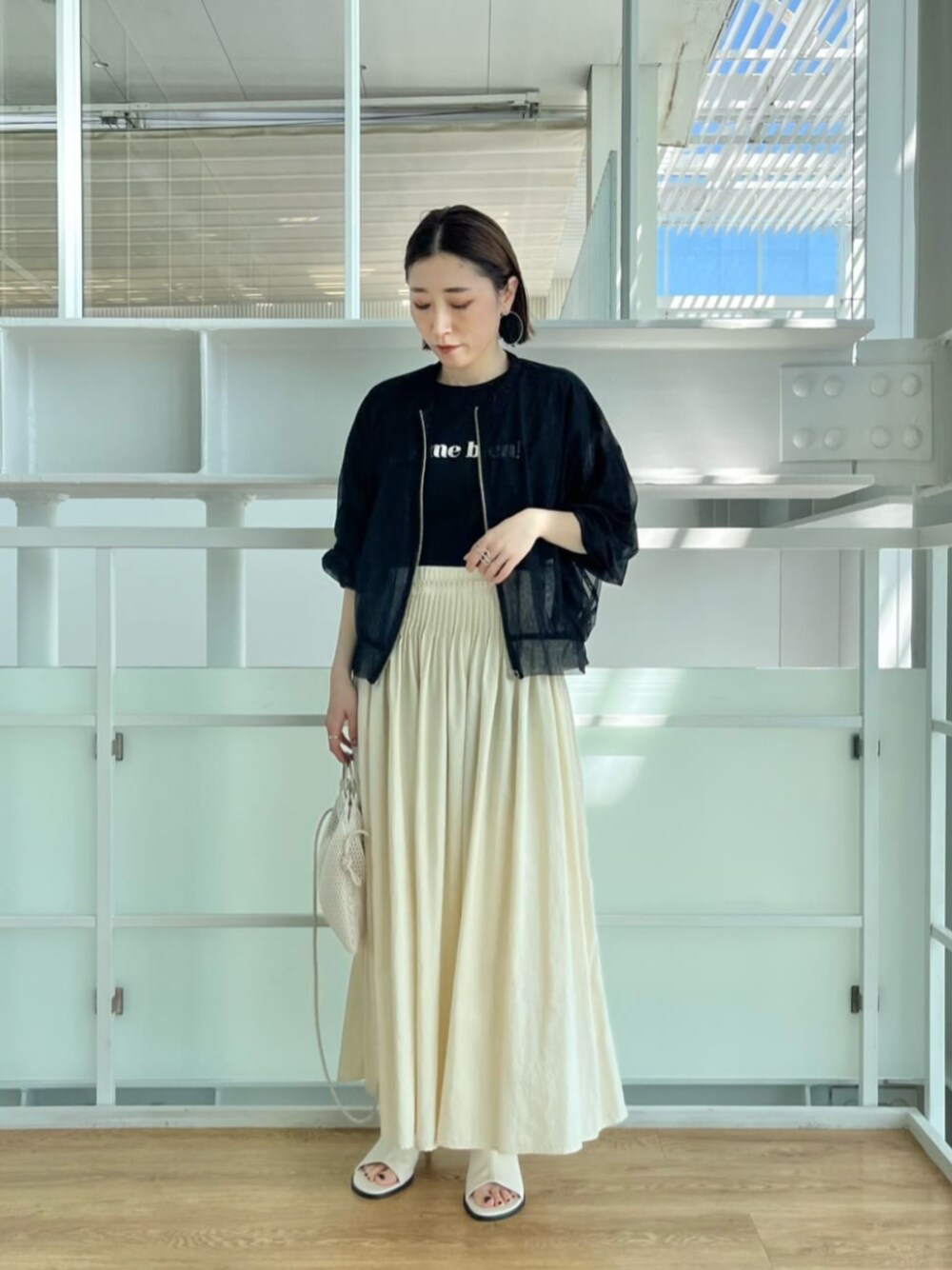 ホワイト系のハンドバッグ、ブラック系のブルゾン、ブラック系のTシャツ/カットソーを着用したレディースの春コーディネートの1枚目の写真