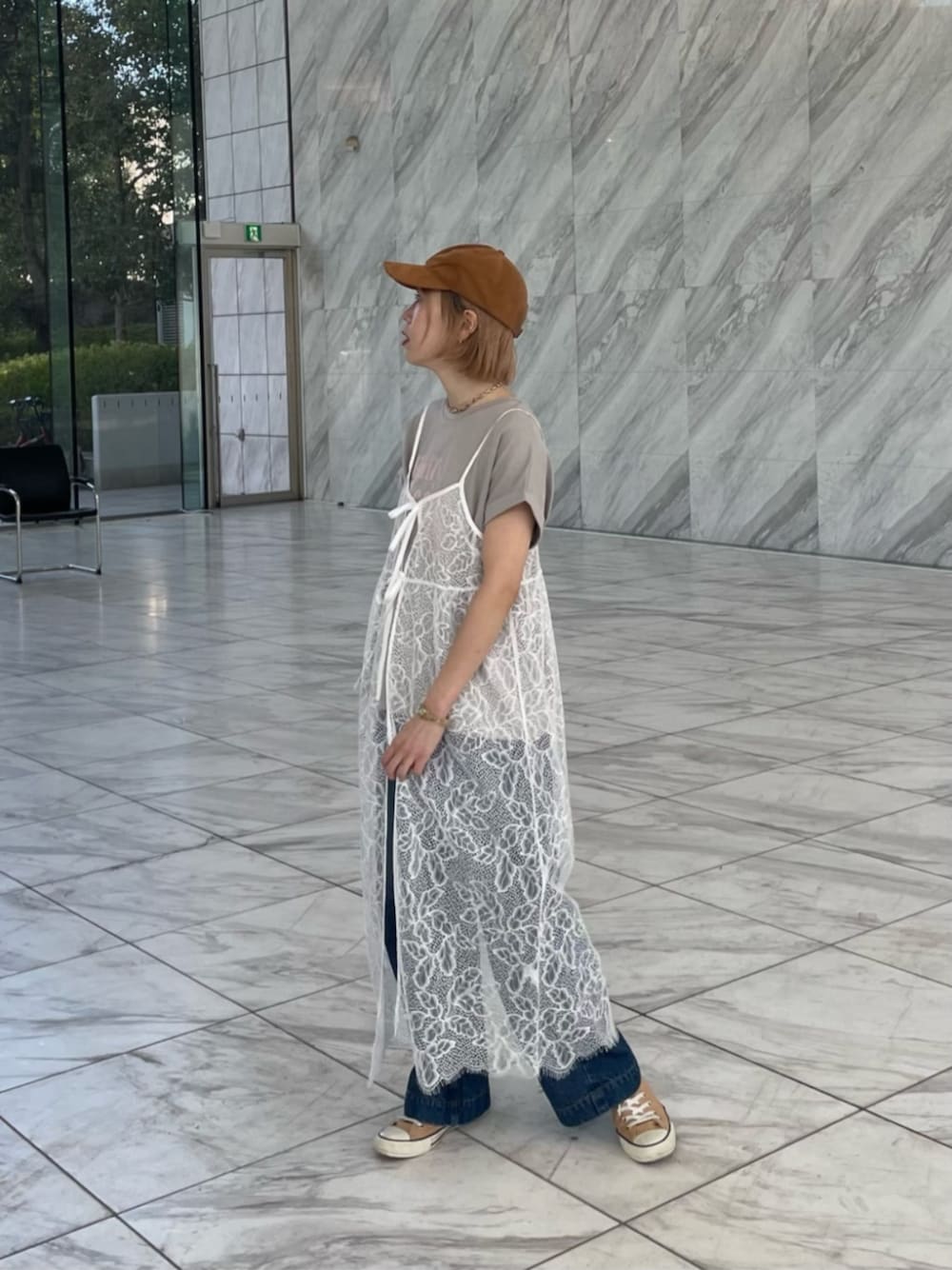 ブルー系のデニムパンツ、グレー系のTシャツ/カットソー、ホワイト系のワンピースを着用したレディースの春コーディネートの1枚目の写真