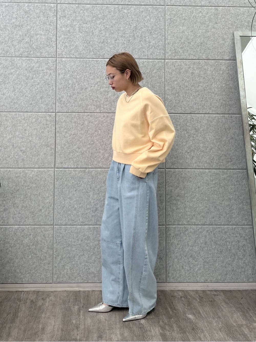 オレンジ系のスウェット、ブルー系のデニムパンツを着用したレディースの春コーディネートの1枚目の写真