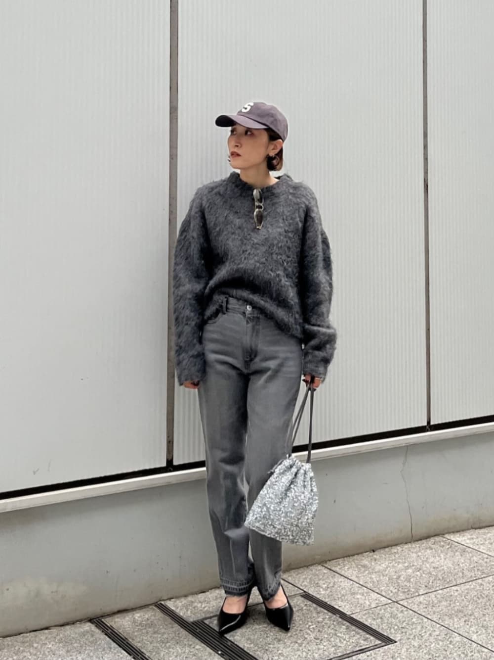シルバー系のショルダーバッグ、グレー系のデニムパンツ、グレー系のニット/セーターを着用したレディースの秋コーディネートの1枚目の写真
