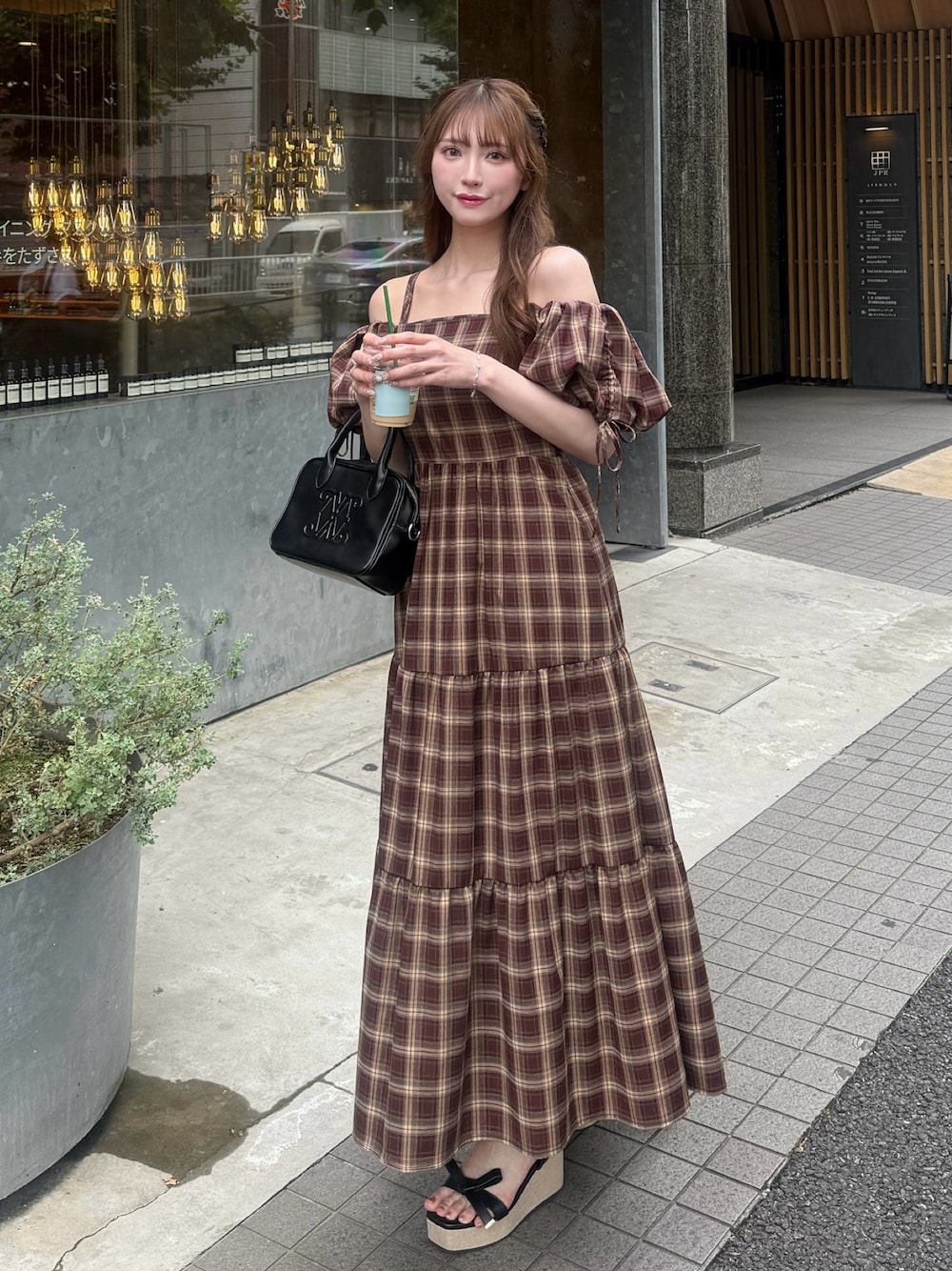 レッド系のワンピース、ブラック系のハンドバッグ、ブラック系のサンダルを着用したレディースの夏コーディネートの1枚目の写真