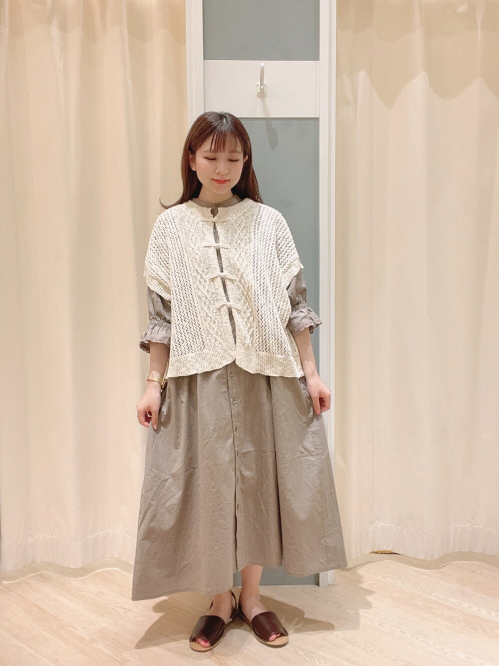 ブラウン系のサンダル、ブラウン系のワンピース、ホワイト系のベストを着用したレディースの夏コーディネートの1枚目の写真