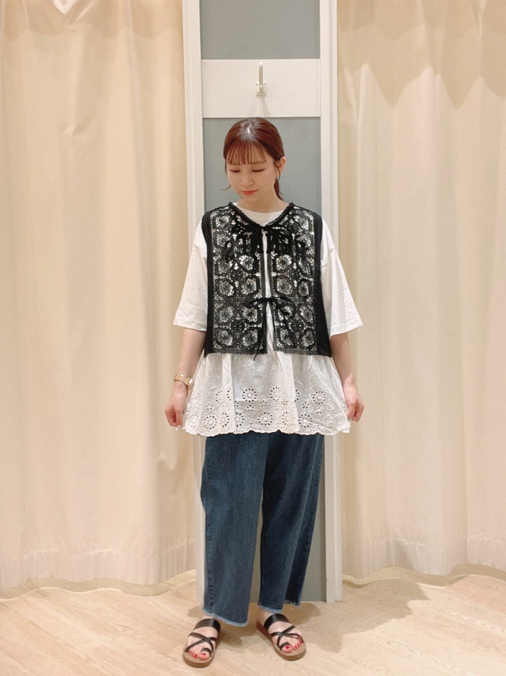 ブラウン系のサンダル、ブルー系のデニムパンツ、ブラック系のベストを着用したレディースの夏コーディネートの1枚目の写真