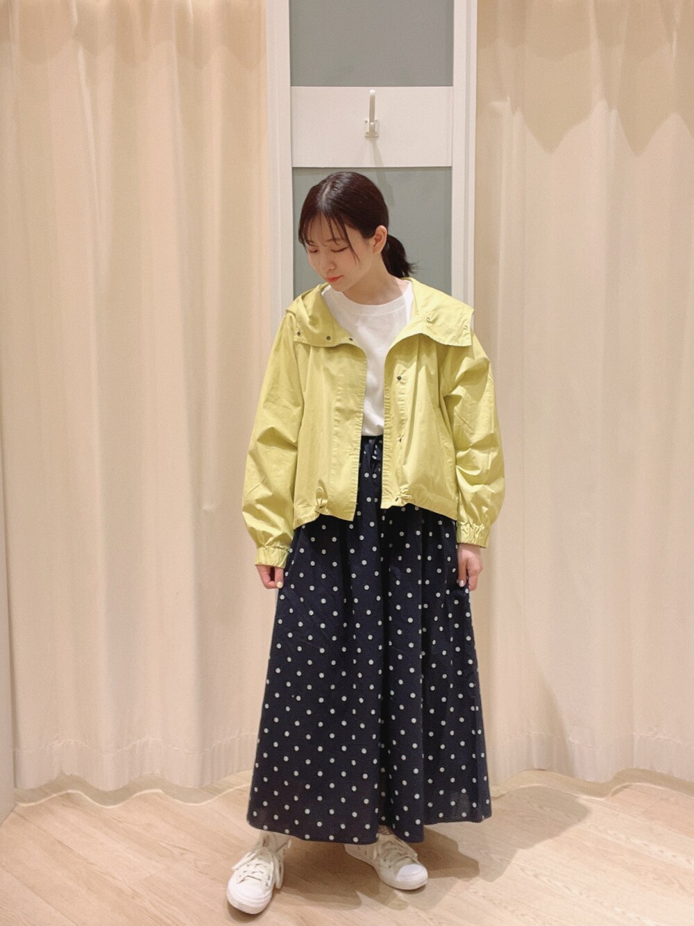 イエロー系のマウンテンパーカー、ホワイト系のTシャツ/カットソー、ホワイト系のスニーカーを着用したレディースの春コーディネートの1枚目の写真