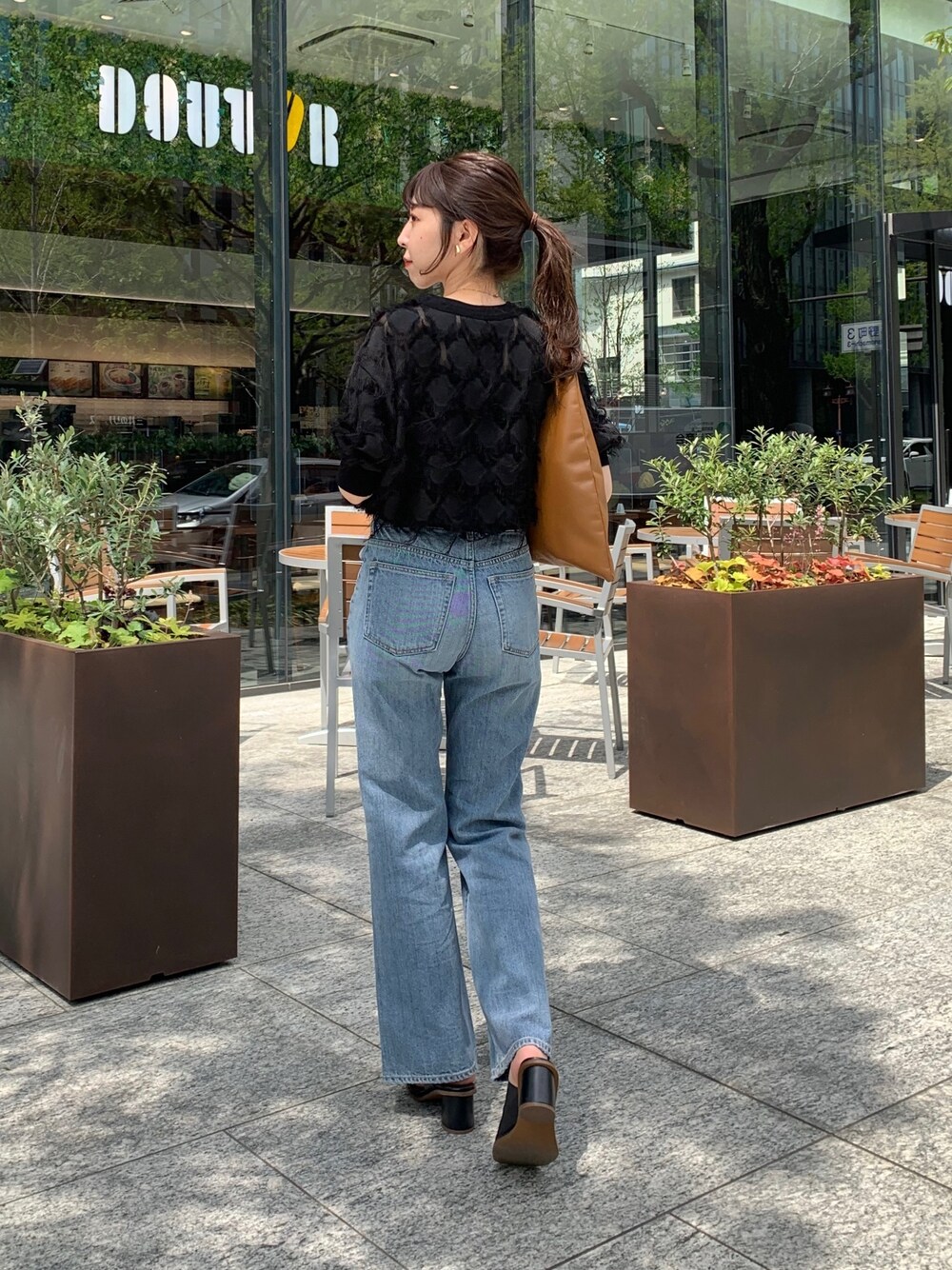 イエロー系のトートバッグ、ブラック系のシャツ/ブラウス、ブルー系のデニムパンツを着用したレディースの春コーディネートの2枚目の写真