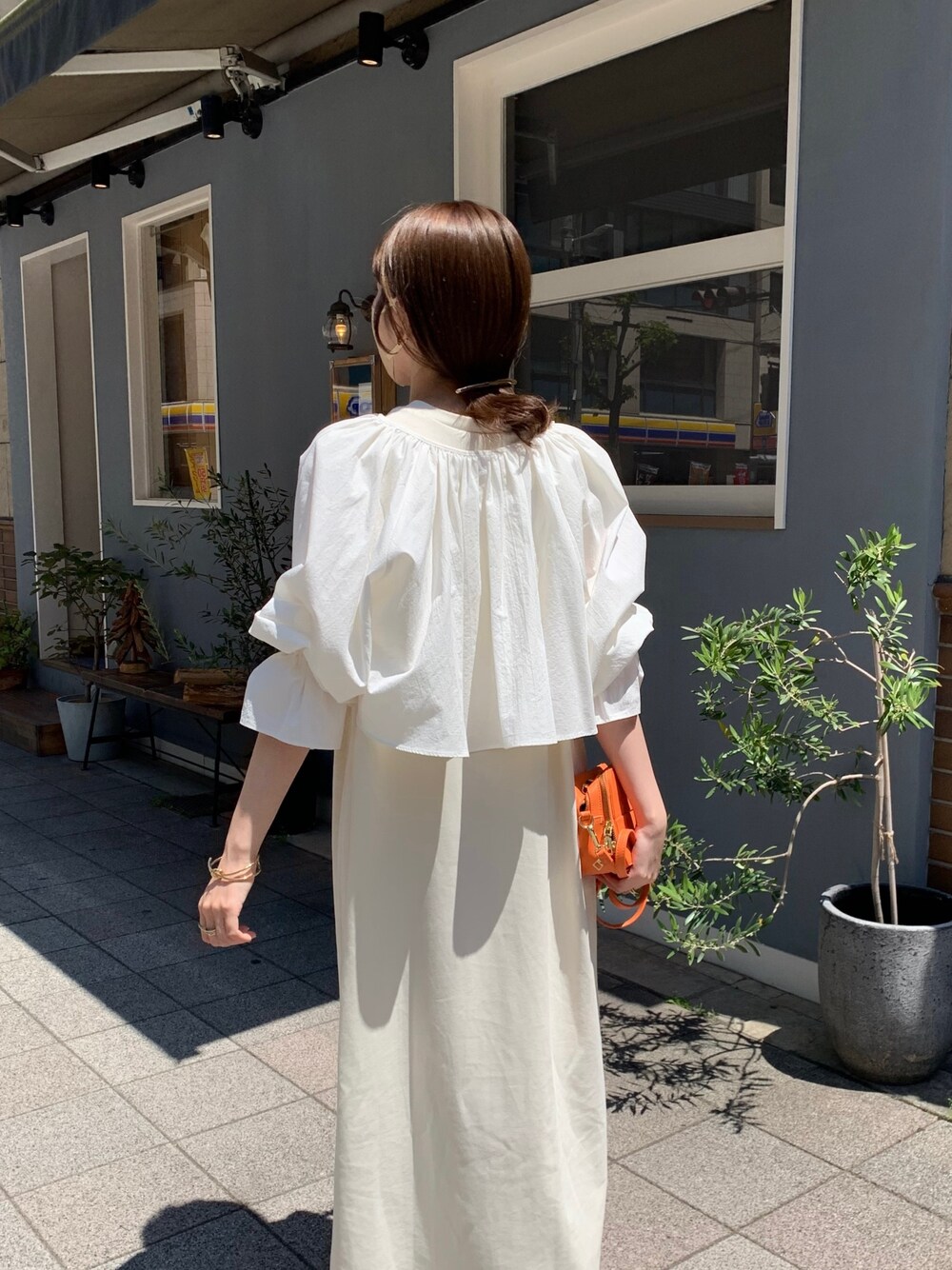 ホワイト系のシャツ/ブラウス、ホワイト系のワンピース、オレンジ系のショルダーバッグを着用したレディースの春コーディネートの3枚目の写真
