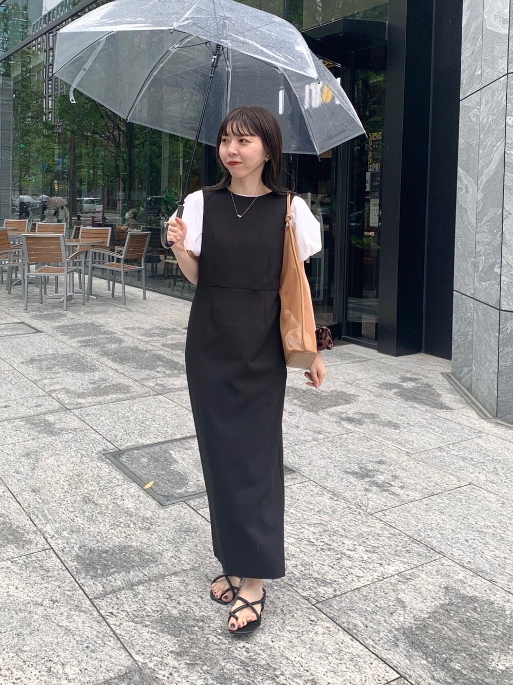 ホワイト系のTシャツ/カットソー、ブラック系のジャンパースカート、ベージュ系のショルダーバッグを着用したレディースの春コーディネートの1枚目の写真