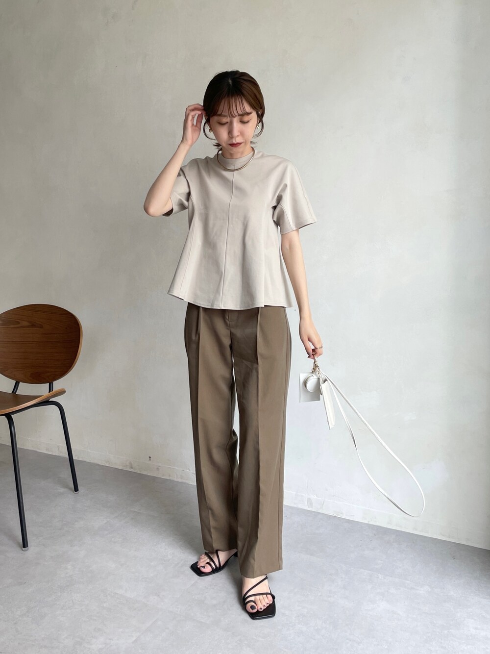 ベージュ系のTシャツ/カットソー、ブラウン系のスラックス、ホワイト系のショルダーバッグを着用したレディースの夏コーディネートの1枚目の写真