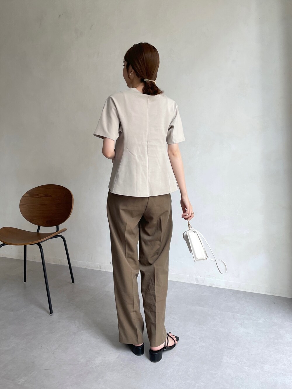 ベージュ系のTシャツ/カットソー、ブラウン系のスラックス、ホワイト系のショルダーバッグを着用したレディースの夏コーディネートの3枚目の写真