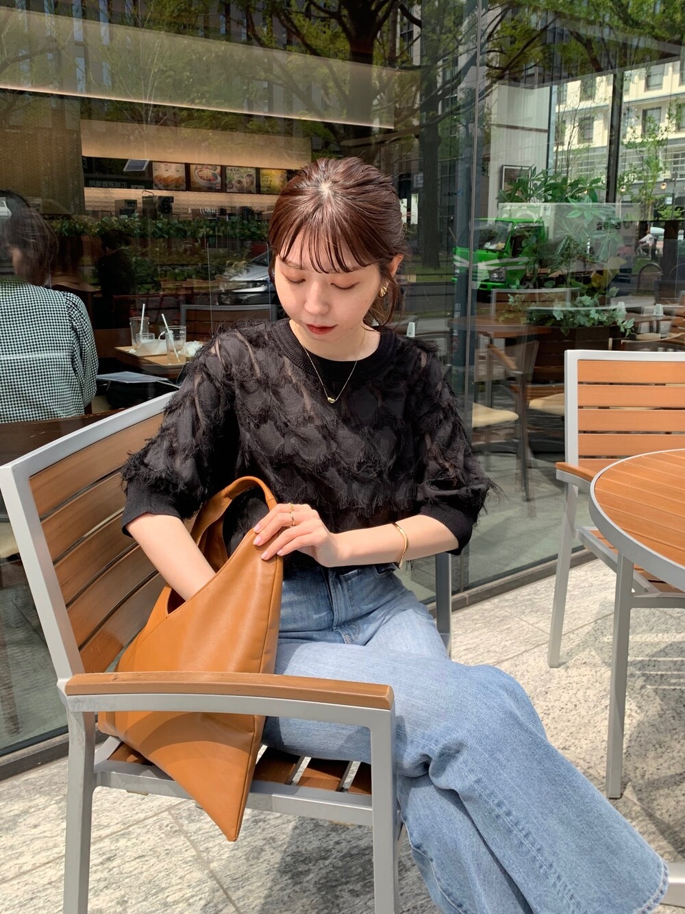 イエロー系のトートバッグ、ブラック系のシャツ/ブラウス、ブルー系のデニムパンツを着用したレディースの春コーディネートの3枚目の写真