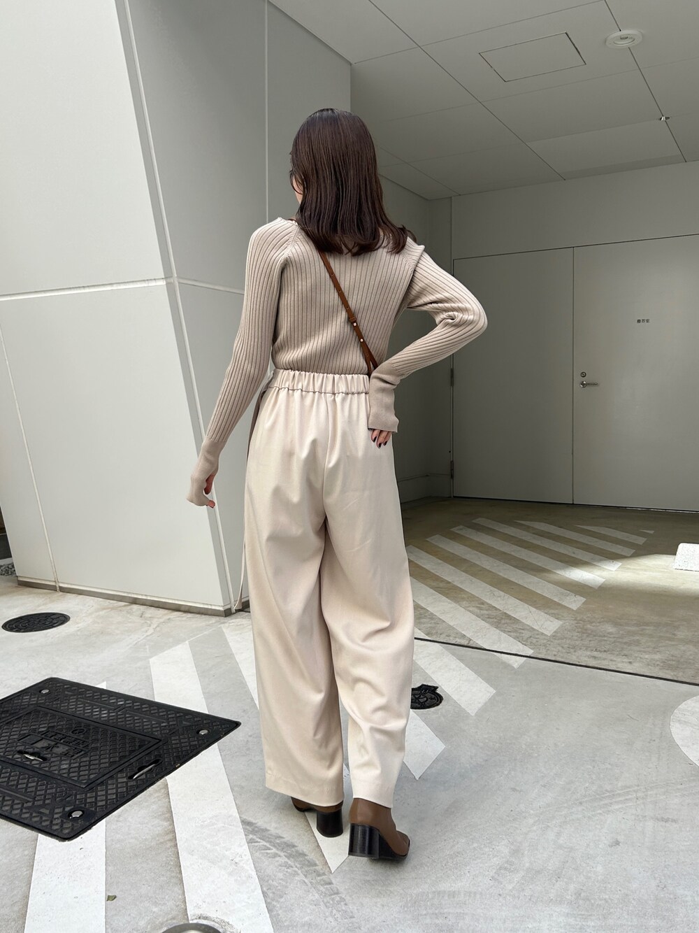 ベージュ系のニット/セーター、ホワイト系のその他パンツ、ブラウン系のハンドバッグを着用したレディースの秋コーディネートの2枚目の写真