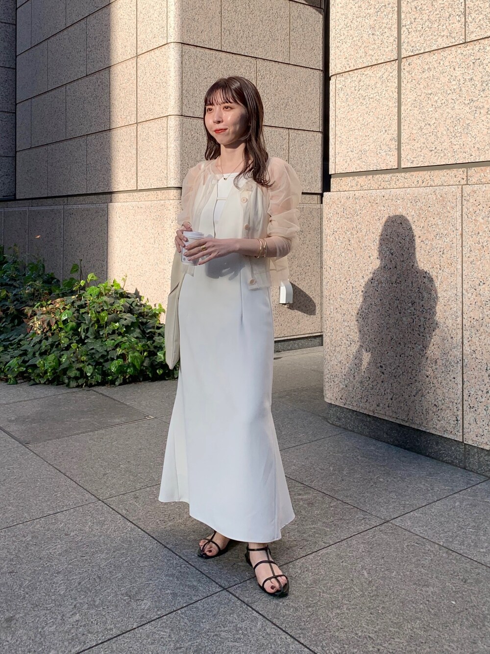 ベージュ系のシャツ/ブラウス、ブラック系のサンダル、ホワイト系のトートバッグを着用したレディースの春コーディネートの1枚目の写真