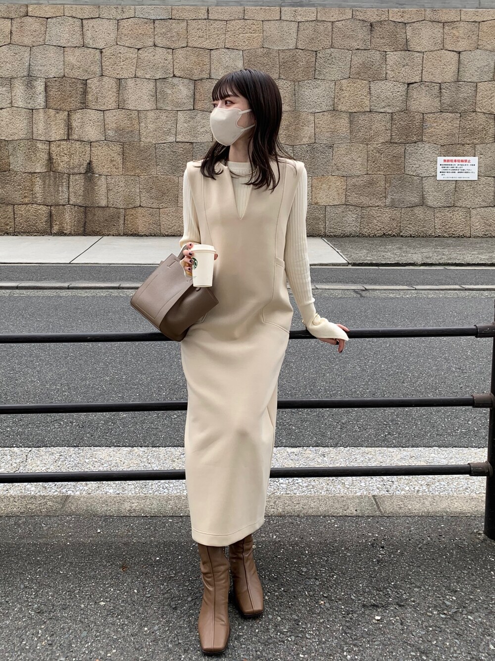 ベージュ系のワンピース、ホワイト系のニット/セーター、ブラウン系のブーツを着用したレディースの秋コーディネートの1枚目の写真