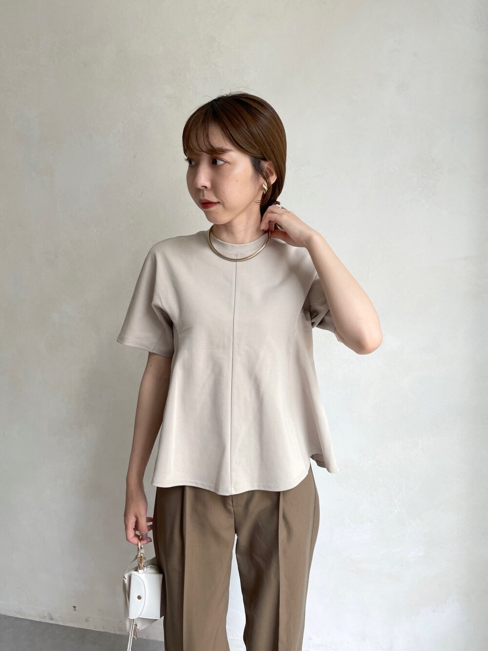 ベージュ系のTシャツ/カットソー、ブラウン系のスラックス、ホワイト系のショルダーバッグを着用したレディースの夏コーディネートの4枚目の写真