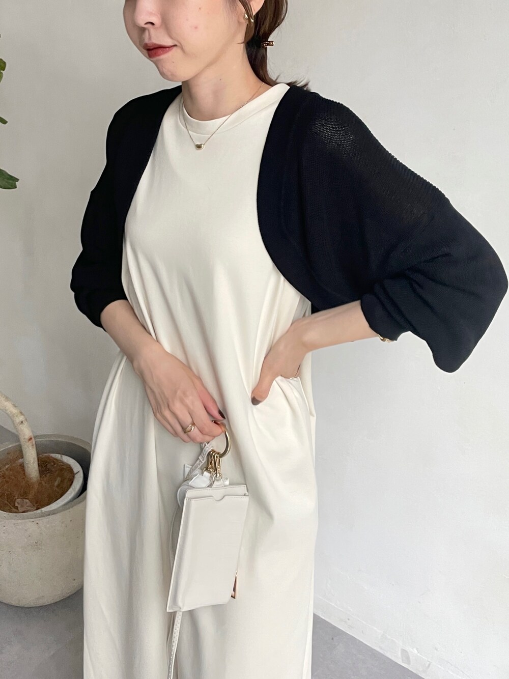 ブラック系のカーディガン/ボレロ、ホワイト系のワンピース、ホワイト系のサンダルを着用したレディースの夏コーディネートの3枚目の写真