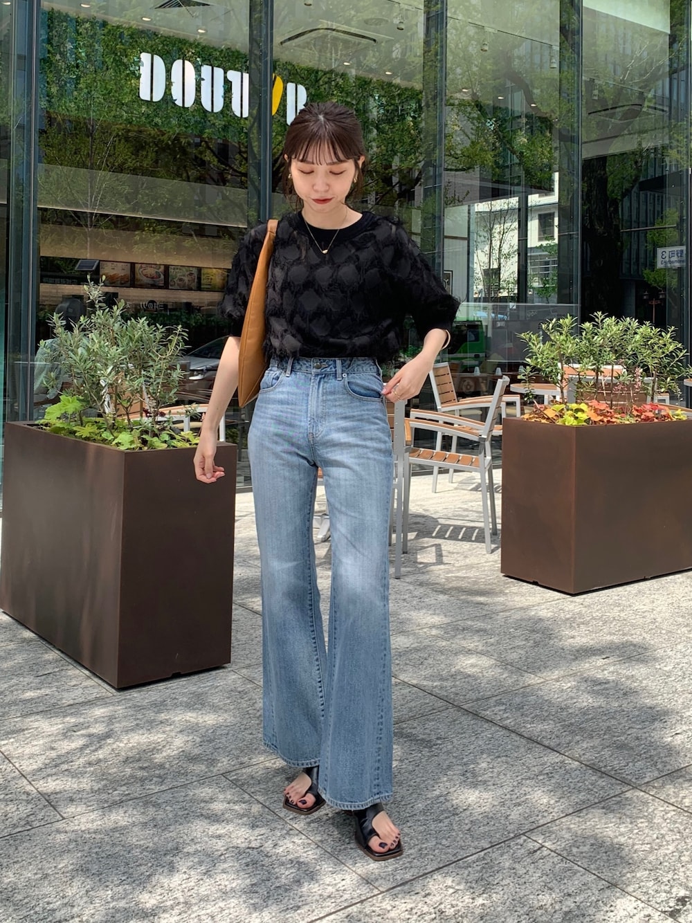 イエロー系のトートバッグ、ブラック系のシャツ/ブラウス、ブルー系のデニムパンツを着用したレディースの春コーディネートの1枚目の写真