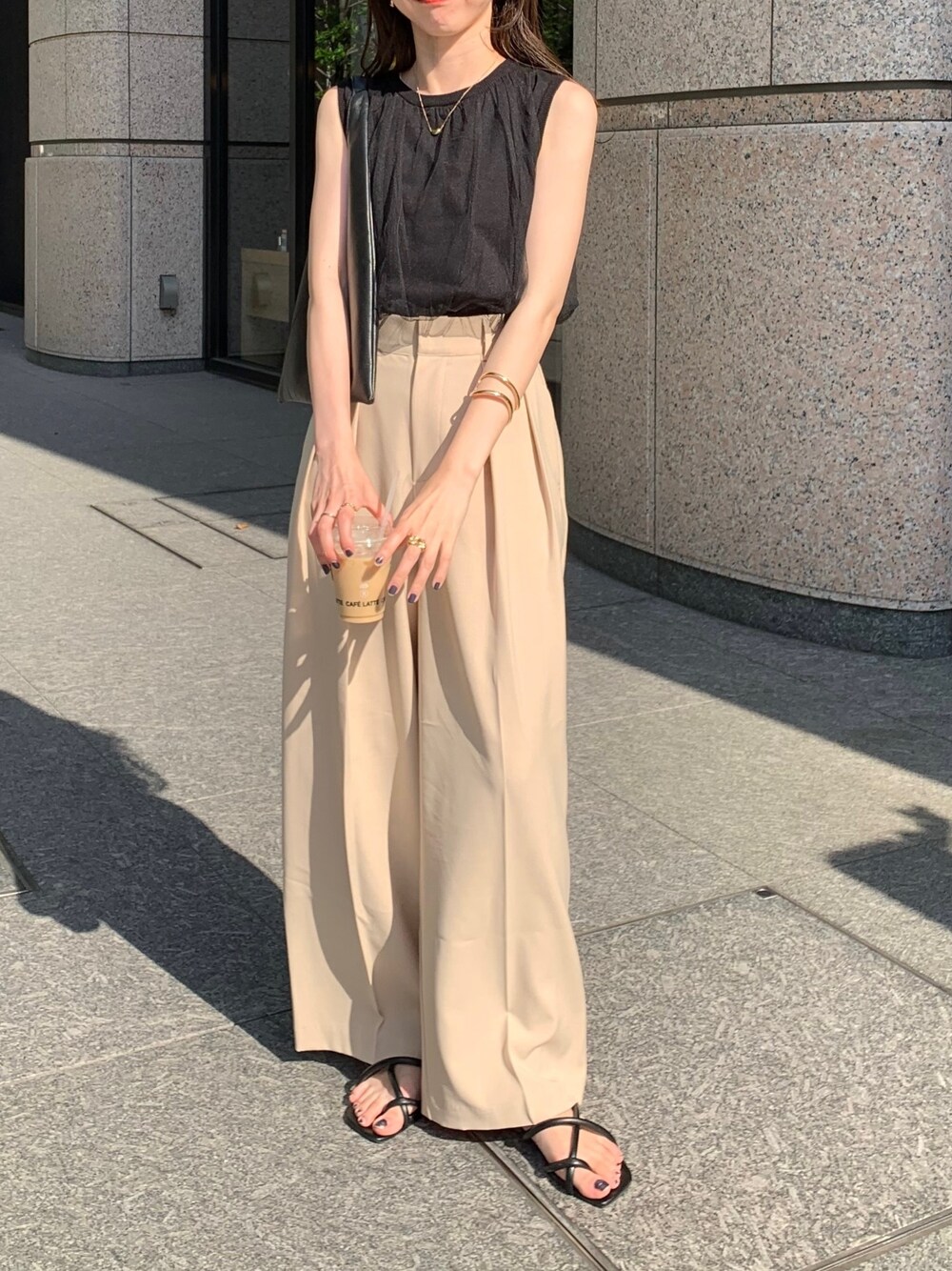 ブラック系のニット/セーター、ベージュ系のその他パンツ、ブラック系のサンダルを着用したレディースの春コーディネートの2枚目の写真