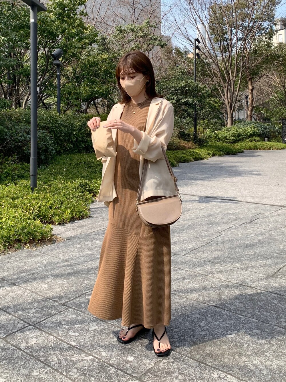 ベージュ系のテーラードジャケット、ブラウン系のワンピース、ブラック系のその他シューズを着用したレディースの春コーディネートの2枚目の写真