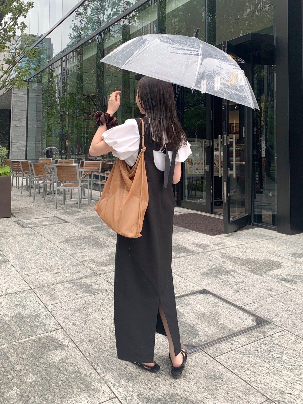 ホワイト系のTシャツ/カットソー、ブラック系のジャンパースカート、ベージュ系のショルダーバッグを着用したレディースの春コーディネートの2枚目の写真