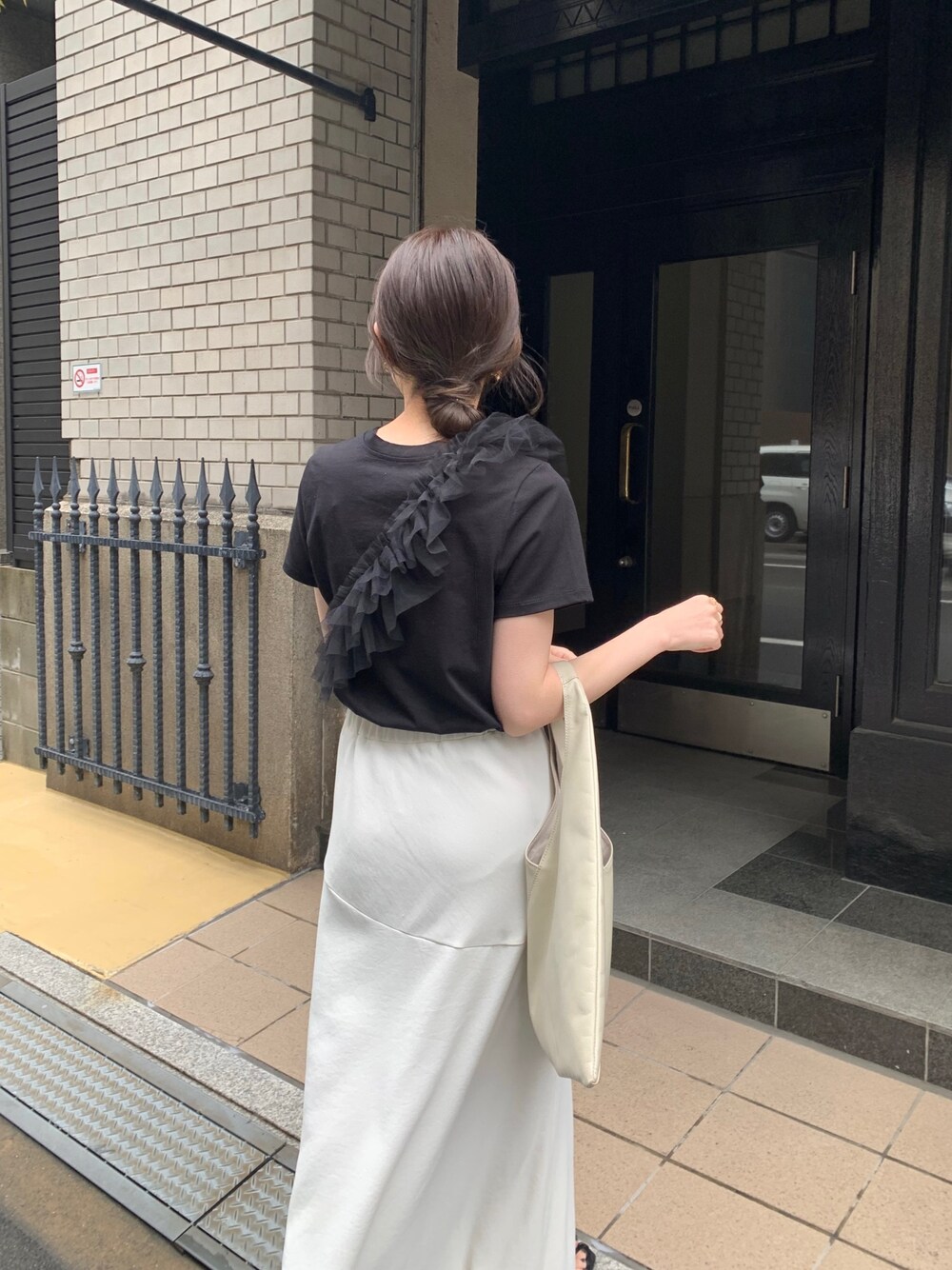 ブラック系のTシャツ/カットソー、ホワイト系のスカート、ホワイト系のトートバッグを着用したレディースの春コーディネートの2枚目の写真