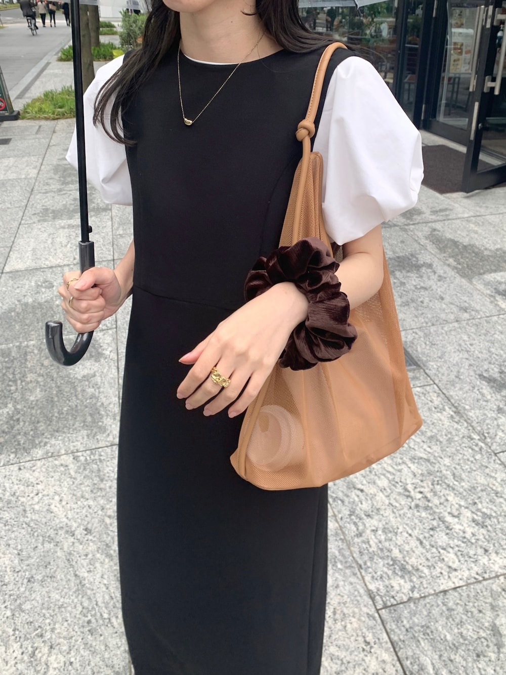 ホワイト系のTシャツ/カットソー、ブラック系のジャンパースカート、ベージュ系のショルダーバッグを着用したレディースの春コーディネートの3枚目の写真