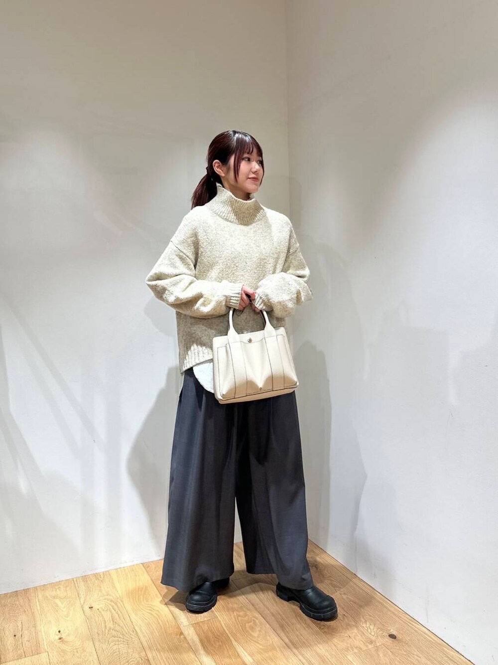 グレー系のその他パンツ、ホワイト系のニット/セーター、ホワイト系のトートバッグを着用したレディースの冬コーディネートの1枚目の写真